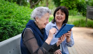older woman reading a tablet with caregiver