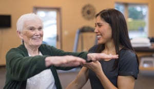 trainer helping older woman exercise