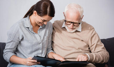 older man and younger female relative looking over a photo album together