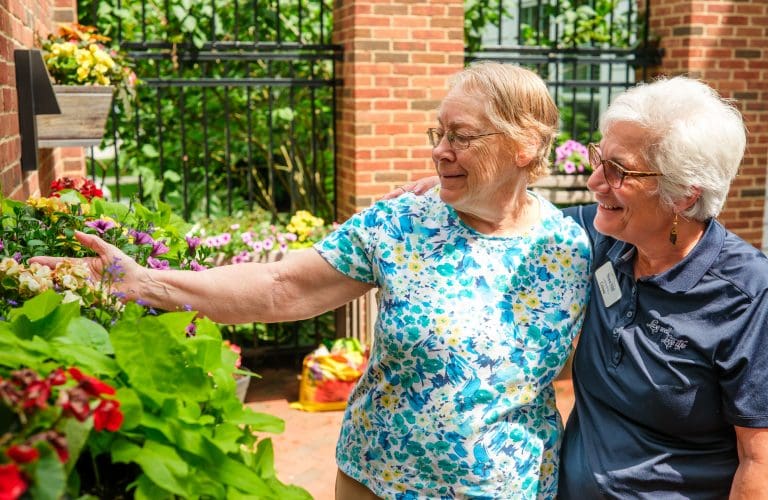 assisted living resident with assisted living program assistant looking at flowers
