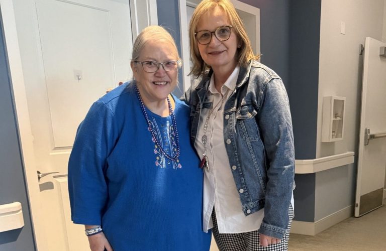 Rita standing with senior living resident in memory care neighborhood