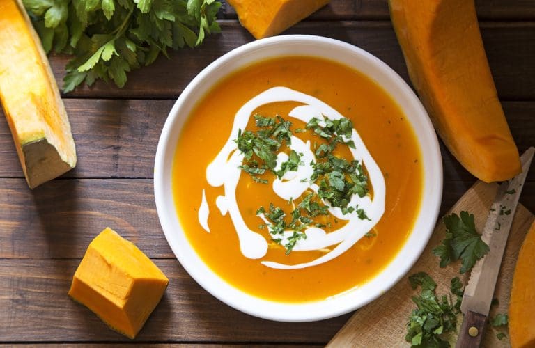 pumpkin soup on cutting board from above with fresh herbs