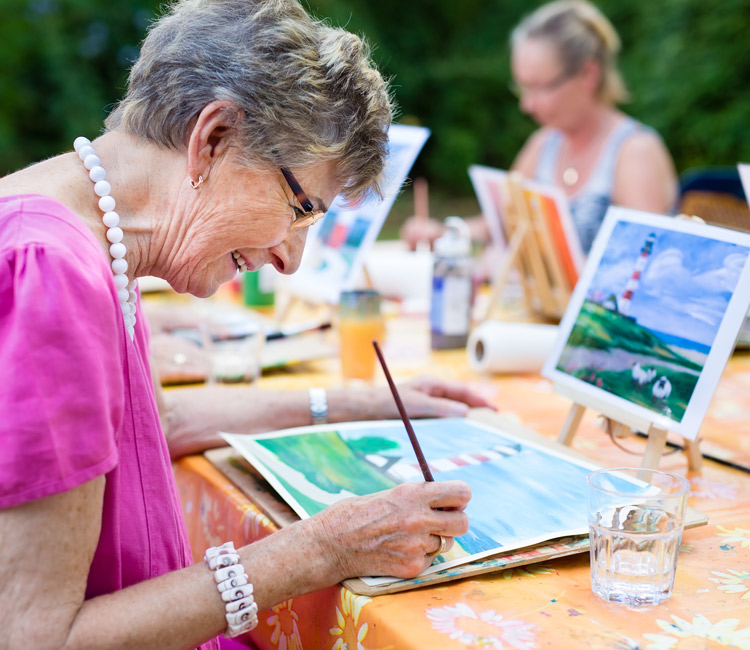 Senior woman smiling while drawing with the group.
