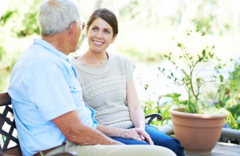 A lovely woman enjoying a conversation with her senior father outdoors