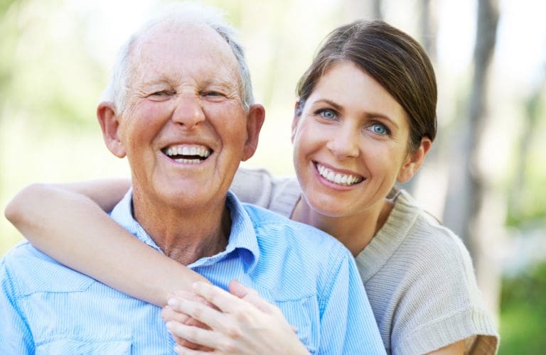 A senior man and his daughter sharing a laugh while out for a walk