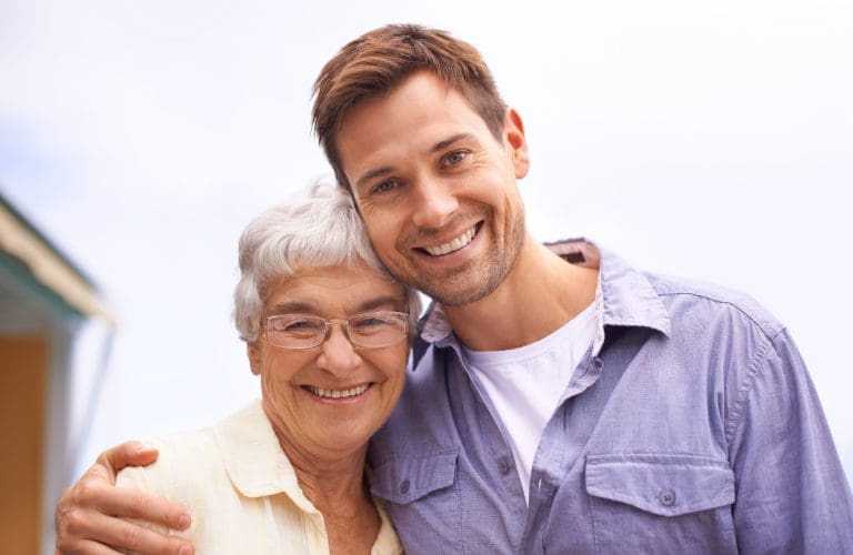 A senior mother and son looking at the camera