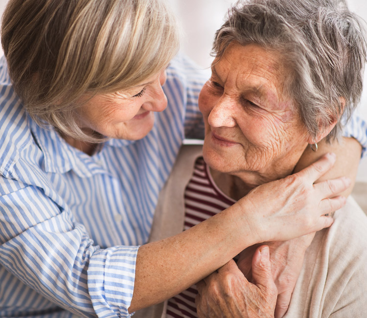 Two senior women at home, hugging. Family and generations concept.
