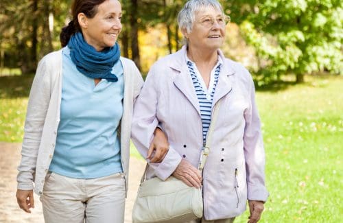 older woman walking with younger woman, linking arms