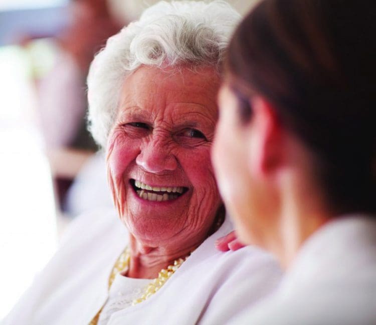 An elderly woman talking and smiling with her nurse